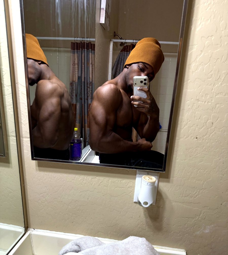 Jamani checking his physique in the bathroom mirror, beanie on